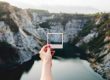 holding Empty polaroid frame over mountain lake